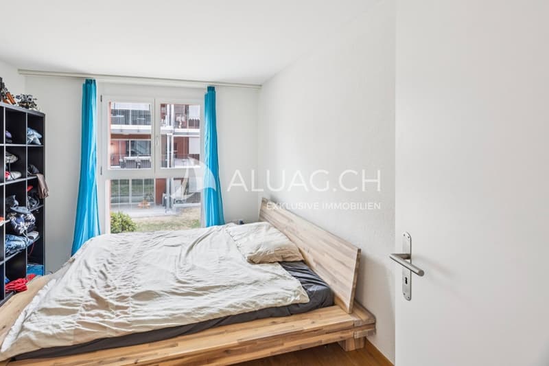 Helles Schlafzimmer mit Parkettboden und grossen Fenstern