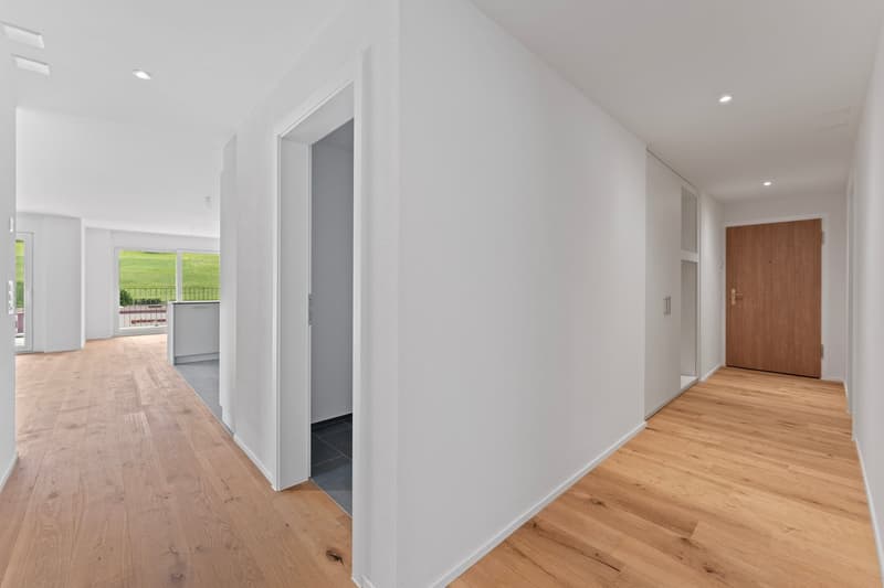 empty hallway with hardwood floors, white walls, wooden door, sliding glass door