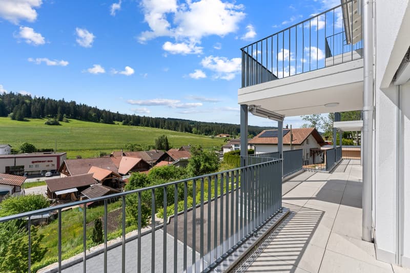 balcony with railings, wide view of countryside, large field, several houses