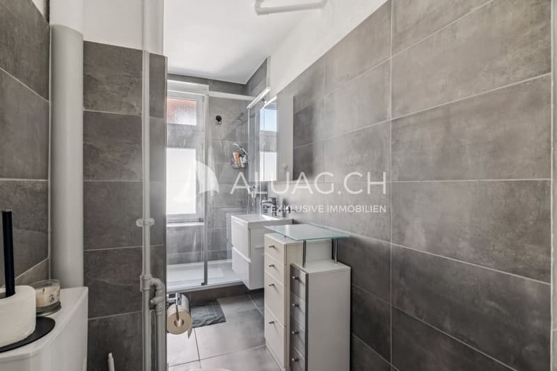 Direkt daneben das moderne Badezimmer mit dunklen Fliesen, Dusche und Fenster gegen Norden.