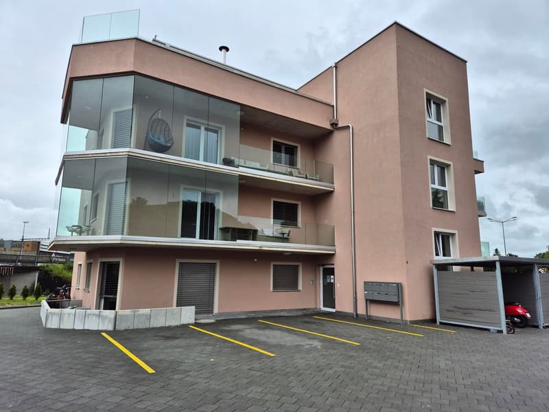 Modern apartment building with glass balconies and parking spaces