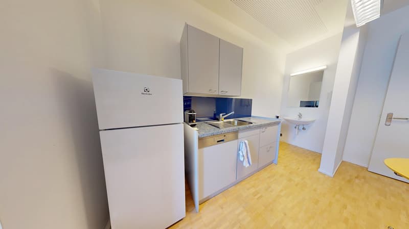 The image shows a modern kitchen with white cabinets, a granite countertop, and a white refrigerator. There is a dishwasher visible in the kitchen.