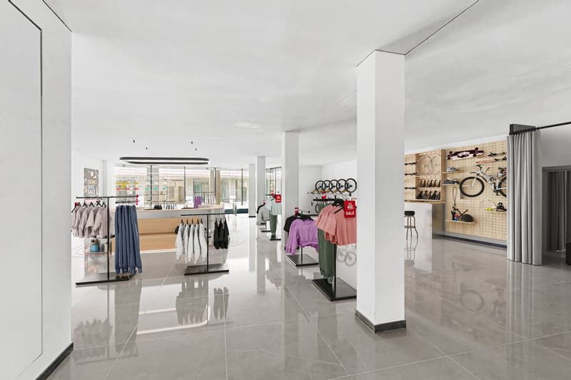 minimalistic store interior with white walls, white pillars, glass displays, bicycles and clothing items on hangers