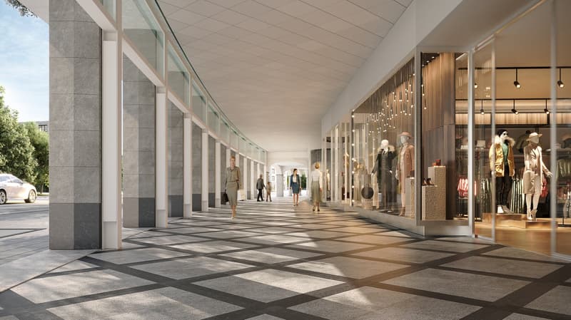 Modern retail arcade, glass columns, tiled floor, several shops, people walking.