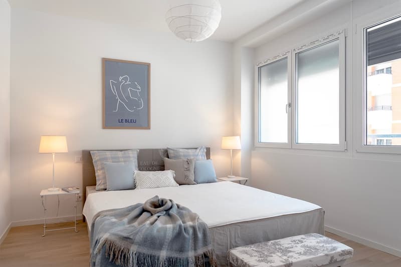 Bedroom with bed, nightstands, lamps, picture frame, and a bench