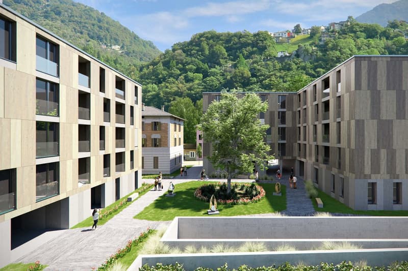 Modern apartment buildings, green space, walking paths, trees, mountains in the background