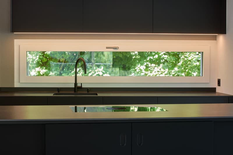 modern kitchen, black cabinets, granite countertops, stainless steel sink, faucet, large window with views of greenery