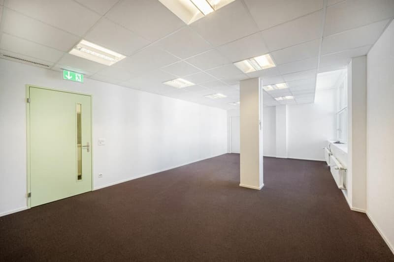 white walls, brown floor, door, radiators, emergency exit sign