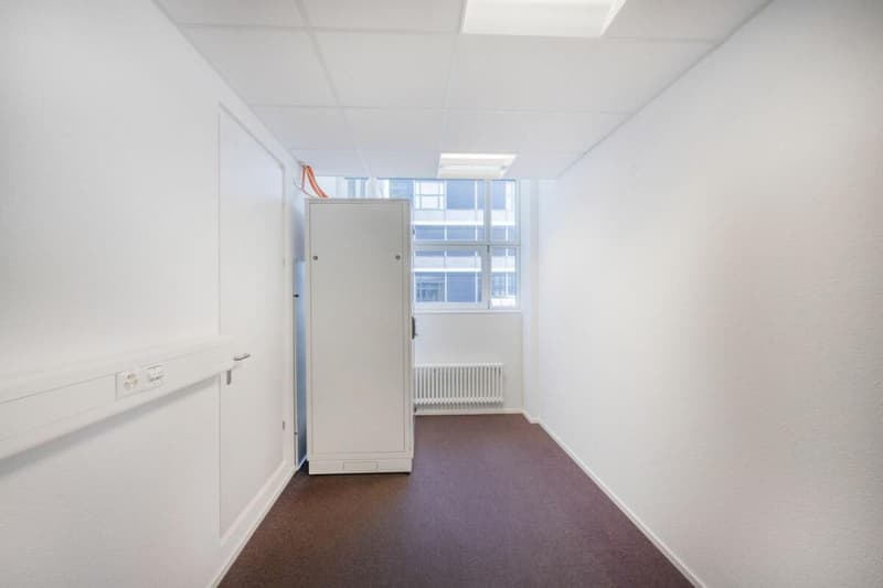 Empty room, white walls, brown floor, radiator, power outlet, open door