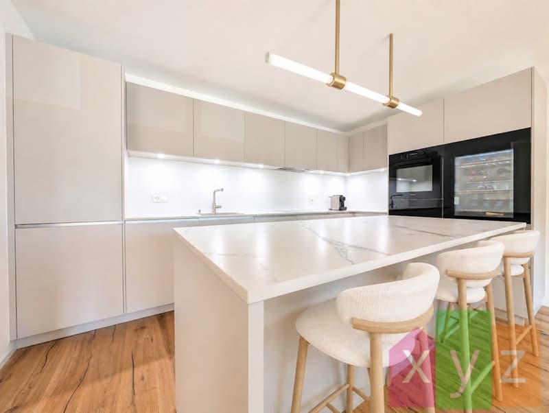 La cuisine ouverte et moderne équipée d'un ilôt central et d'appareils électroménagers Miele dont une cave à vin intégrée et un four pyrolyse