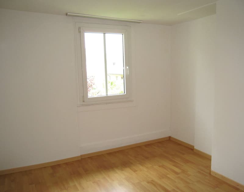 Empty room with hardwood floor, white walls, and a window.