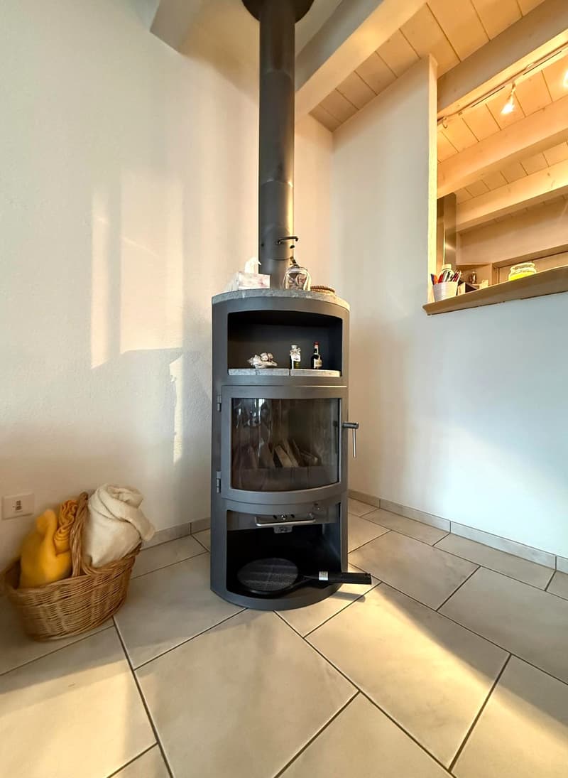A fireplace, tiled floor, white walls, wicker basket with towels, small shelf with bottles