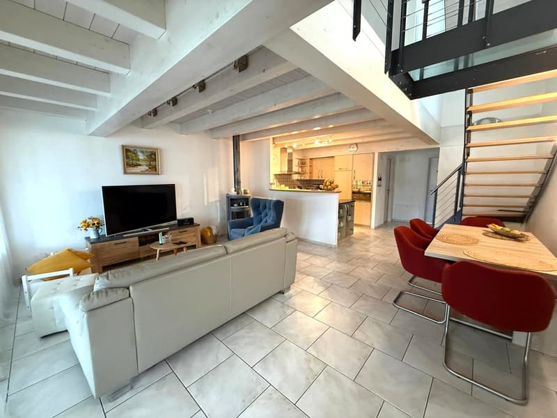 white leather couch, white marble flooring, modern dining set, 2 blue armchairs, wooden table, open staircase, kitchen at the back, flat-screen TV