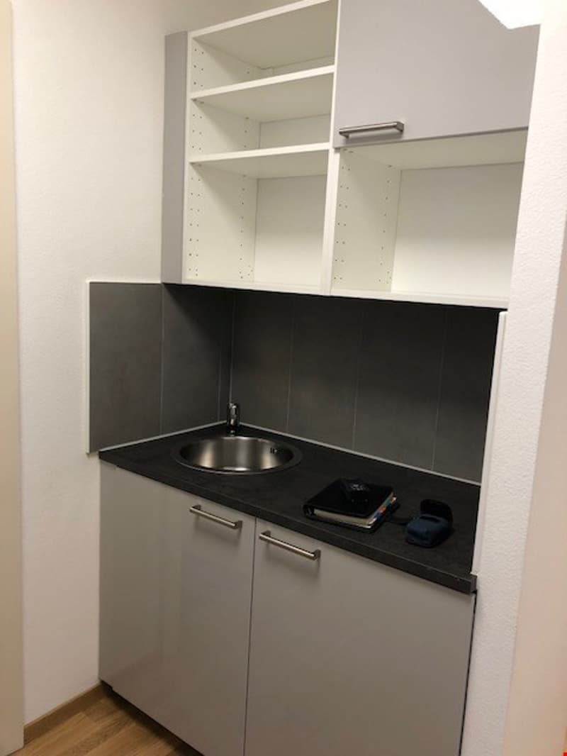 white cabinets, gray shelves, gray backsplash, silver sink, silver faucet, induction stove top, black countertop