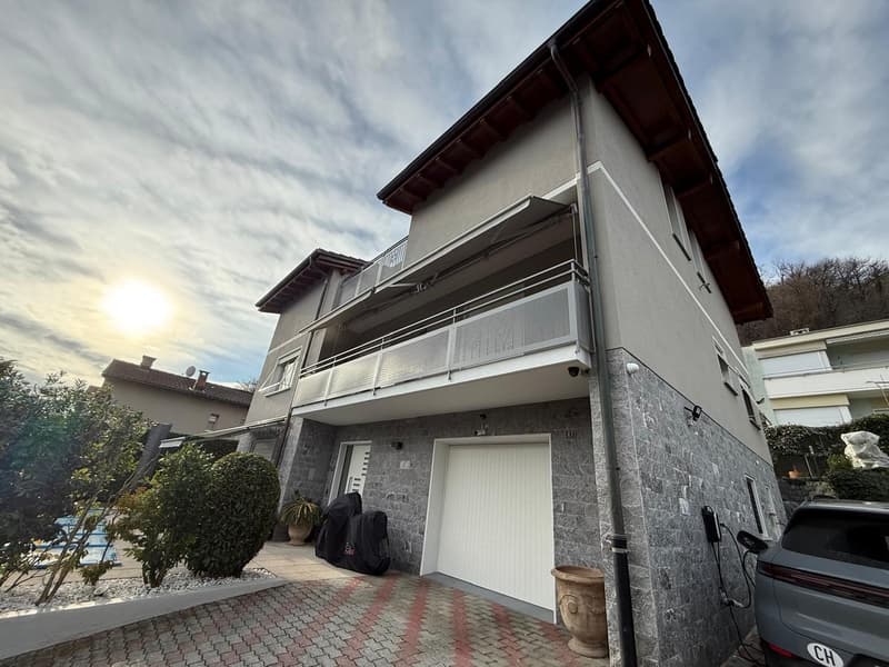 2 story house, gray stone exterior, white garage, balcony, car parked in front