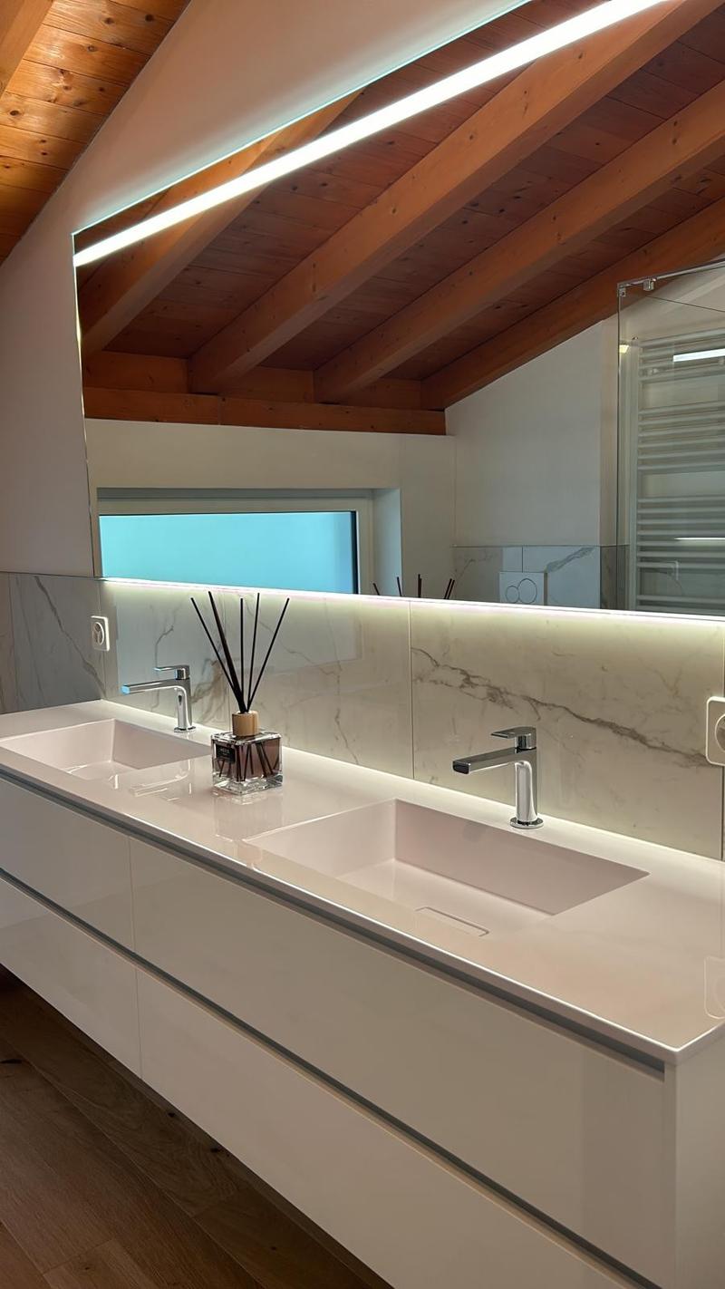 modern bathroom with double sink, large mirror, wooden ceiling, white marble countertop, two faucets, wooden floor