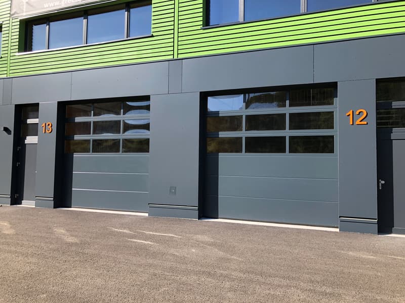 2-story commercial building with green and gray exterior, large windows, and garage doors