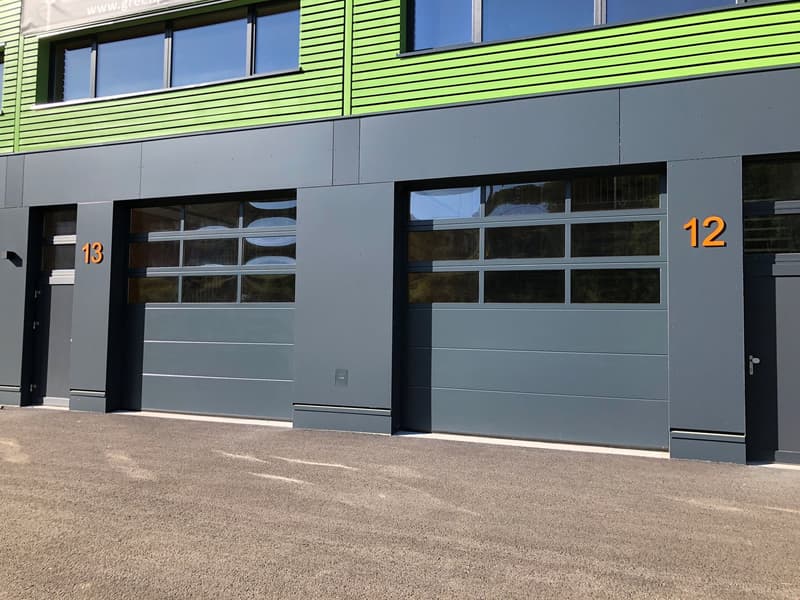 2-story commercial building with green and gray exterior, large windows, and garage doors