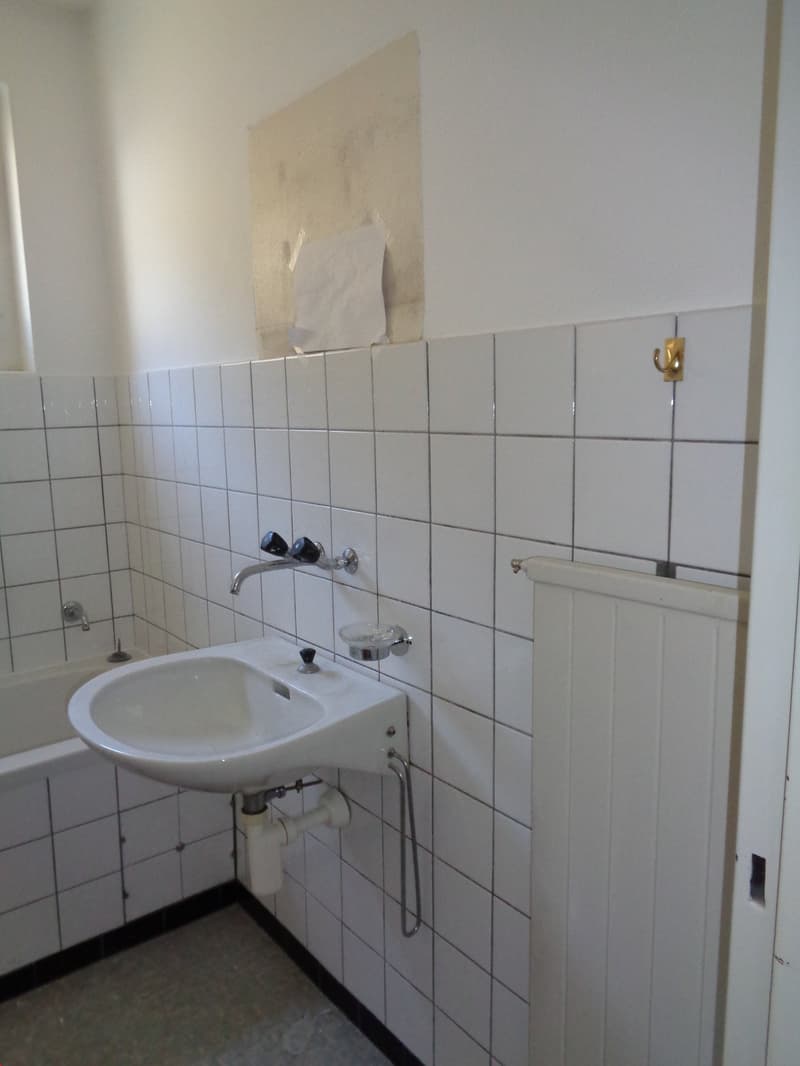 white tile walls, bathtub, sink with faucet, white radiator, small shelf