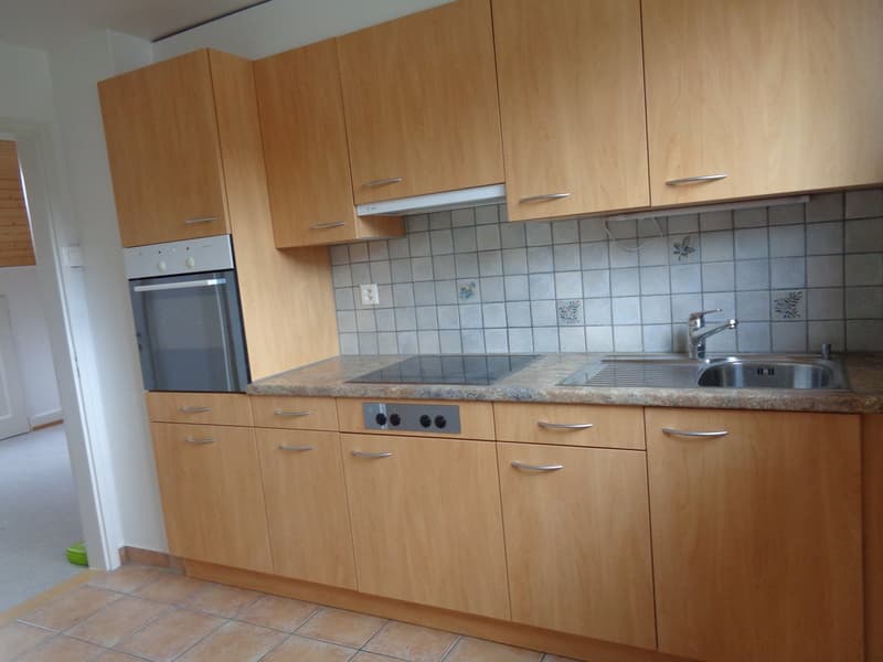 Modern kitchen with wooden cabinetry, countertop, electric stove, sink, faucet, and a microwave