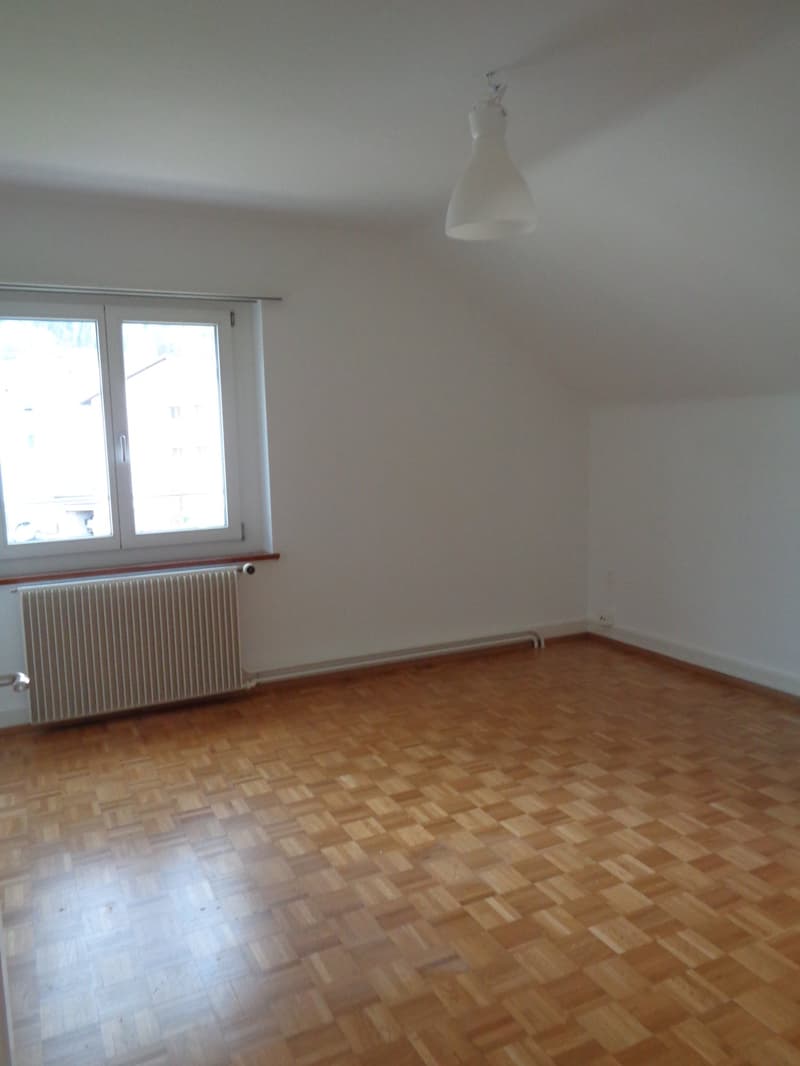 white walls, wooden floors, a window with a white radiator, a ceiling lamp