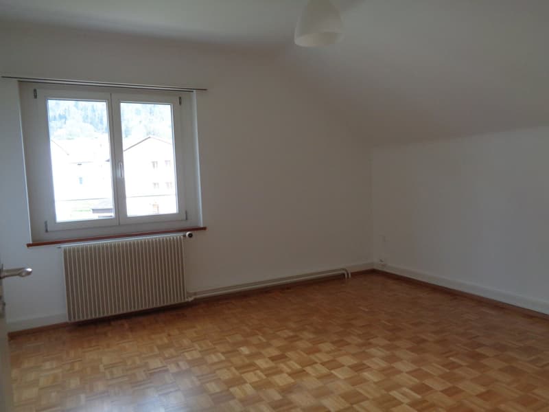 Empty room with white walls, wooden floor, a white window and a white heater