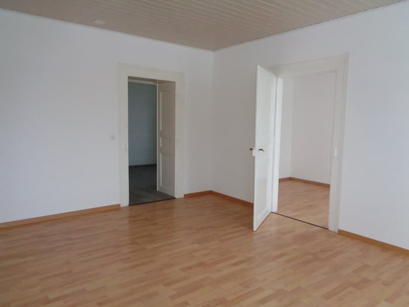 empty room with white walls, wooden floors, two open doors