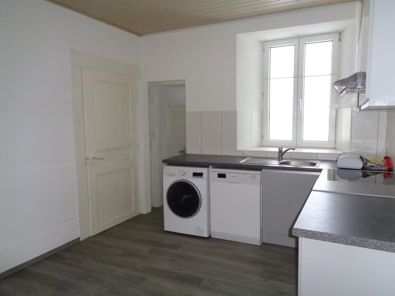 large windows, washer, dryer, sink, kitchen counter, granite countertop, white cabinets