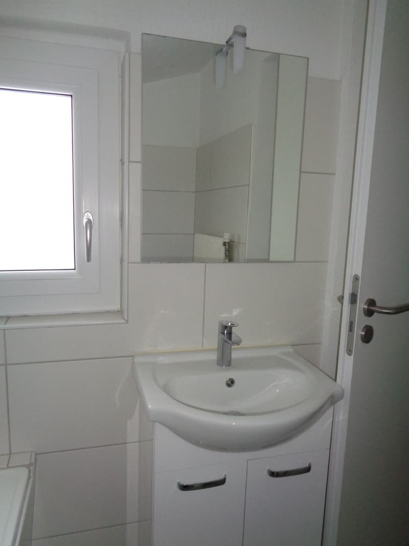 white tiled walls, white sink, white cabinet, mirror with lamps