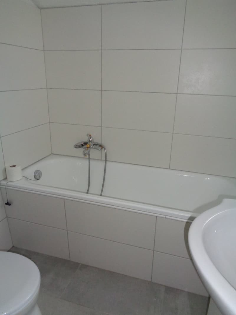 All white bathroom with bathtub, sink, and toilet.