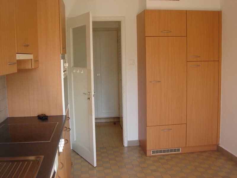 kitchen with wooden cabinets, tiled floor, open door, sink, countertop, oven, dishwasher, washing machine