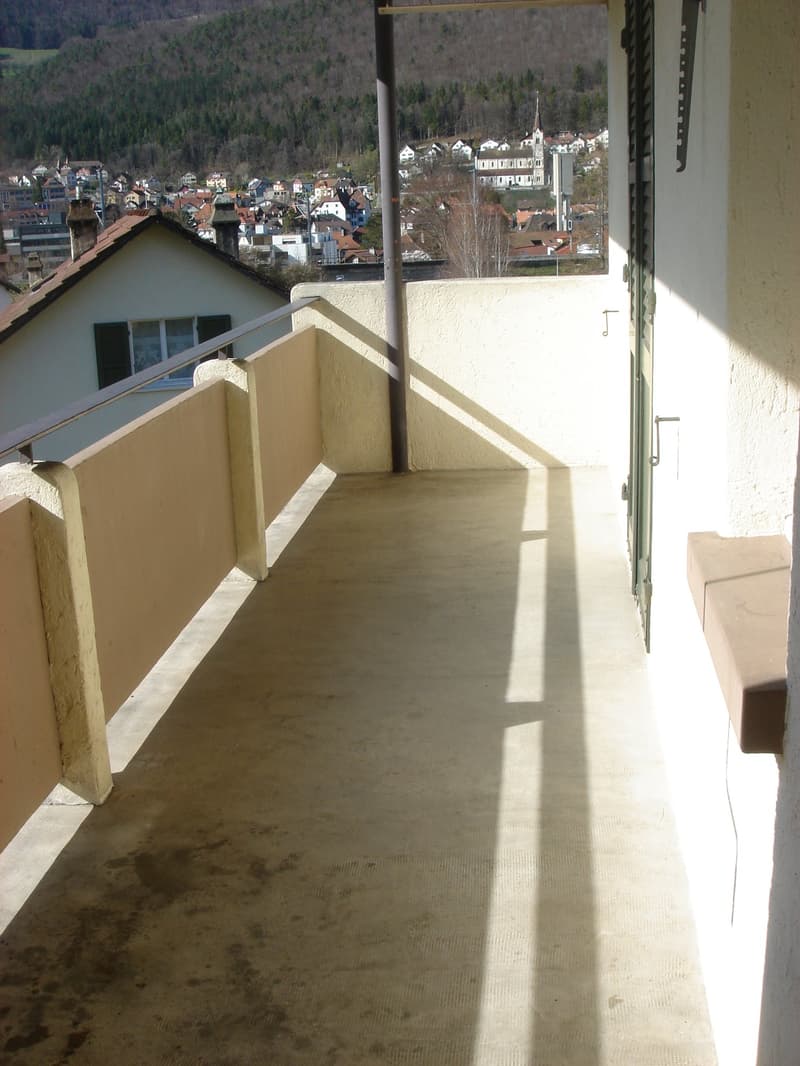 Balcony with concrete floor, metal railing, and a view of the town
