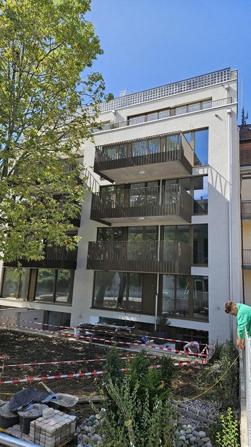 5-story building, balconies on each floor, glass walls, construction zone at the front