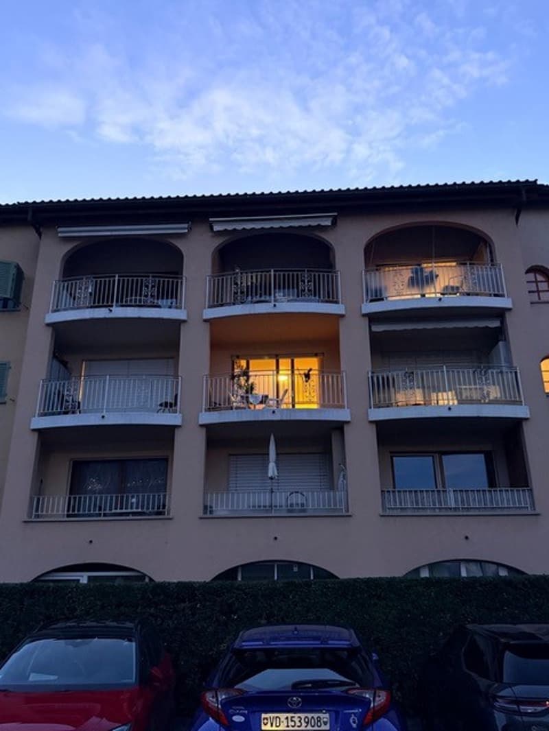 4 story building, beige exterior, balconies, cars parked in front