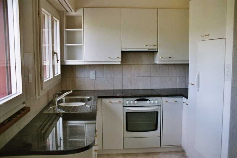 White cupboards, black granite countertop, stainless steel sink, silver faucet, white refrigerator, white stove with oven