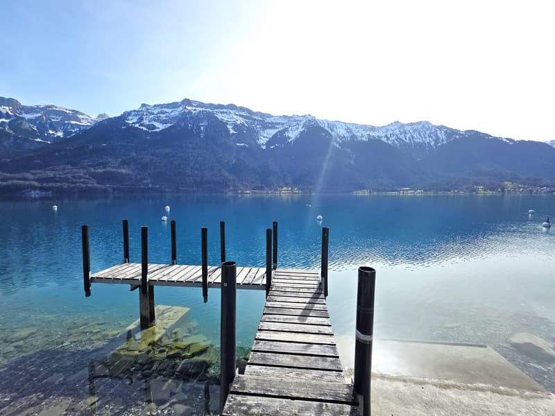 wooden dock, blue lake, mountains, clear sky