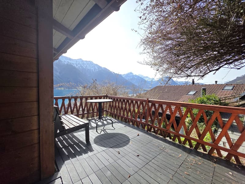 wooden balcony with railings, wooden bench, small table, mountain view
