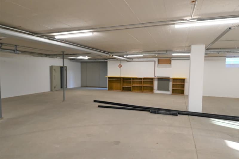 empty large underground garage, white walls, wooden cabinets, long fluorescent lights