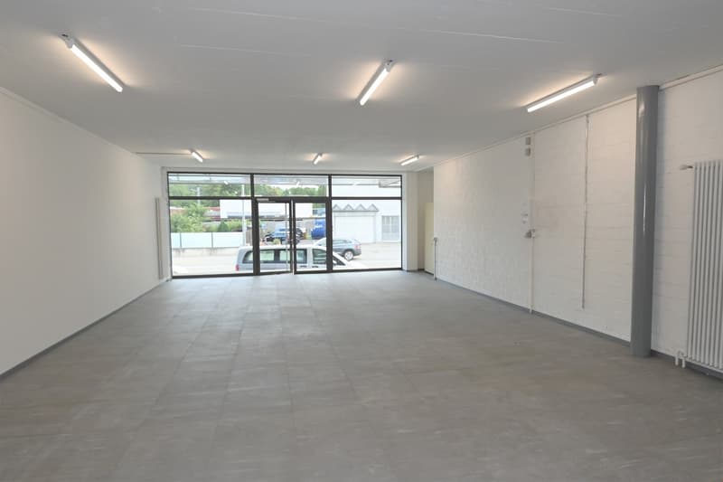 empty room, white walls, gray floor, large windows, fluorescent ceiling lights