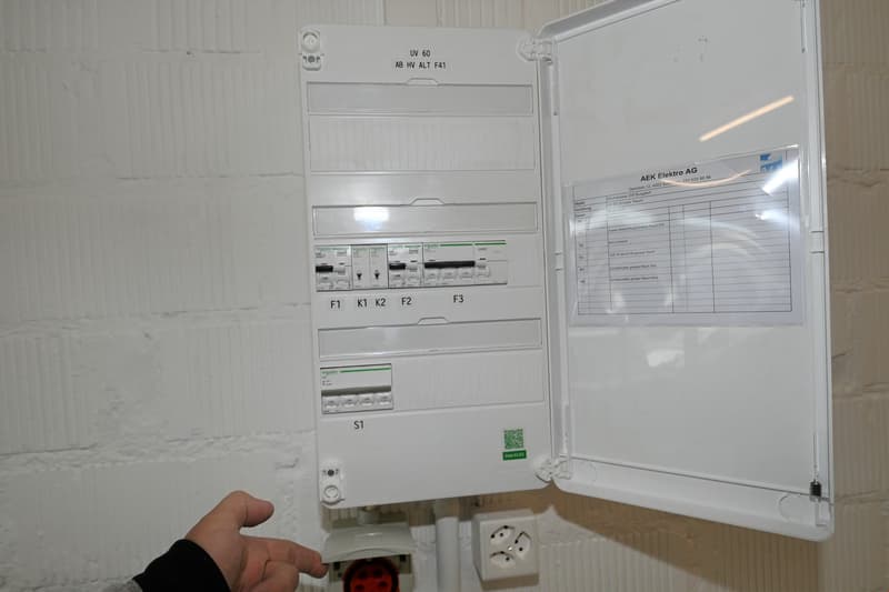 Open electrical panel with multiple switches and a paper with text