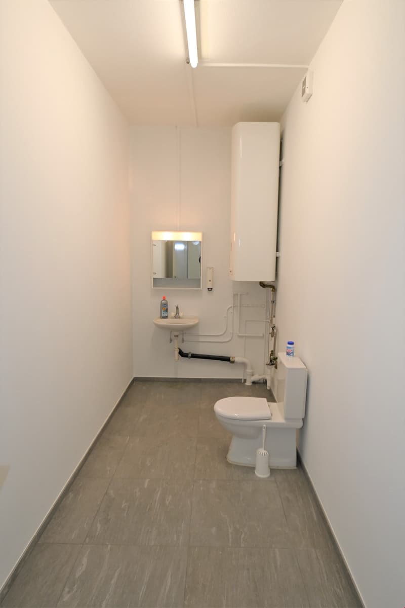 small bathroom with toilet, sink, mirror, and water heater