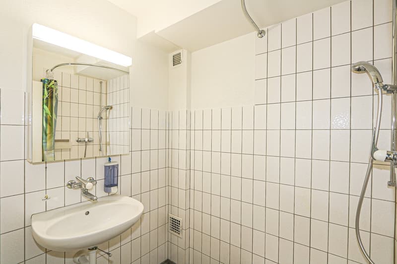 White tiles, shower head, faucet, soap dispenser, mirror, white sink, curved shower rail