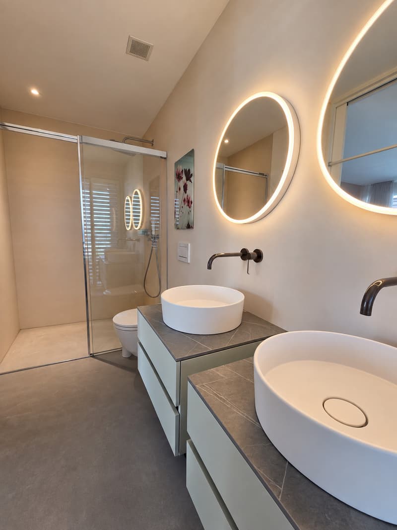 ein modernes Badezimmer mit runden Spiegeln an der Wand und einer großen begehbaren Dusche / a modern bathroom with circular mirrors on the wall and a large walk - in shower