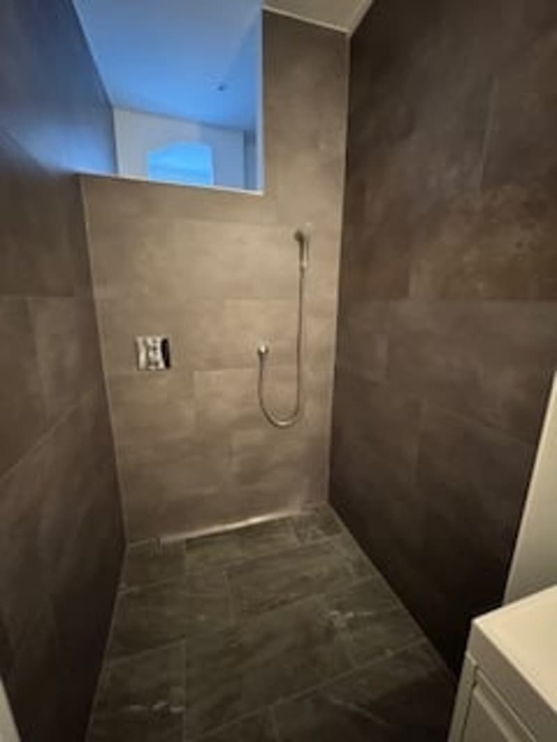 shower room with gray tiles, shower head, power outlet