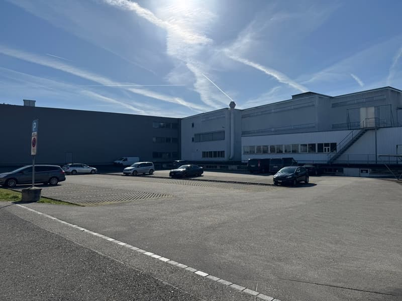 a large industrial building with several cars parked in front