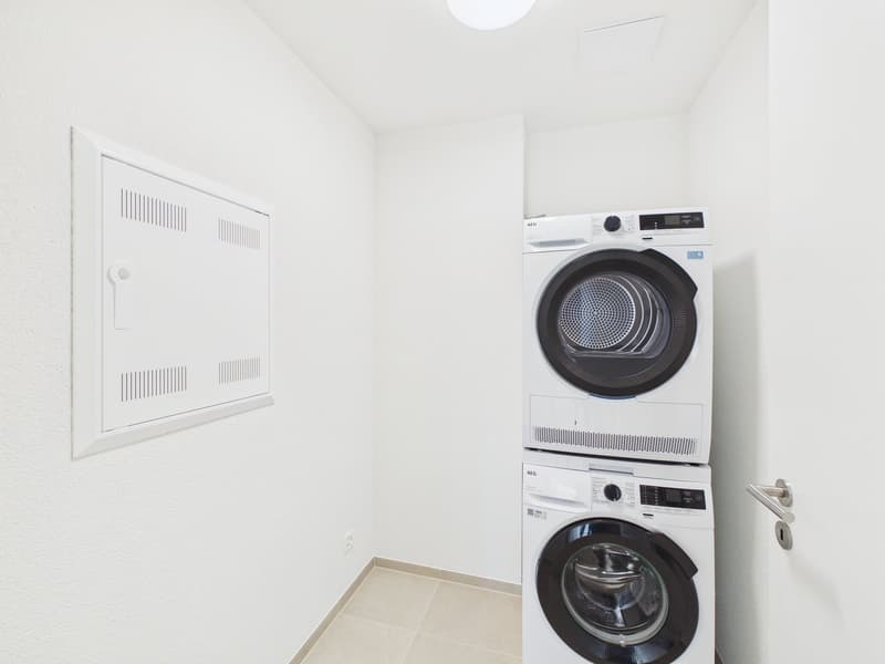 A small laundry room with a washing machine and a dryer stacked on top of each other.