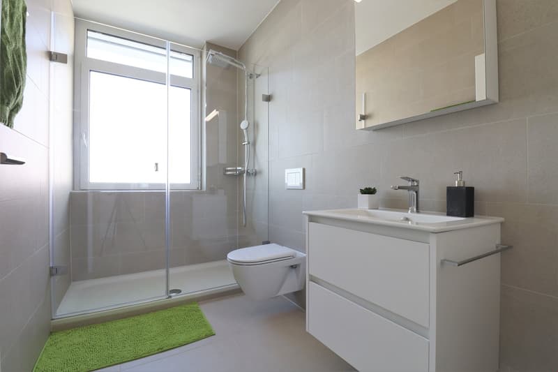modern bathroom with shower, toilet, sink, and mirror