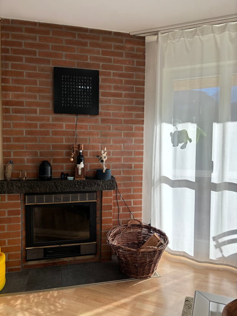 Brick wall, fireplace with decor, wicker basket, curtains, hardwood floor