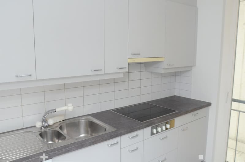 White cabinets, granite countertop, stainless steel sink, built-in oven, gas stove, and a window