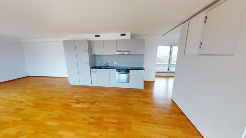 Empty kitchen with wooden floor, white cabinets, modern appliances, and a large window